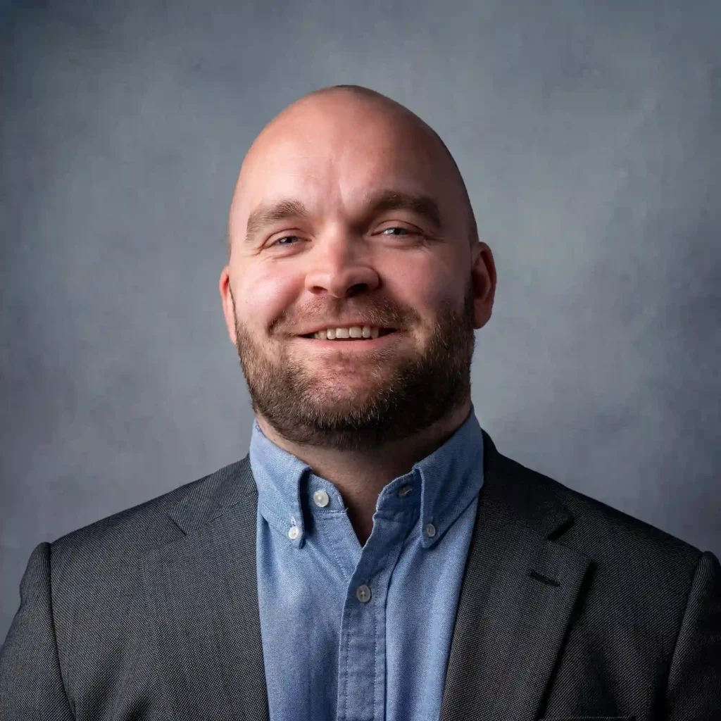 Personalbild av en glad, skallig man med skägg i grå kavaj, fotograferad i Arvika av fotograf Pixpep