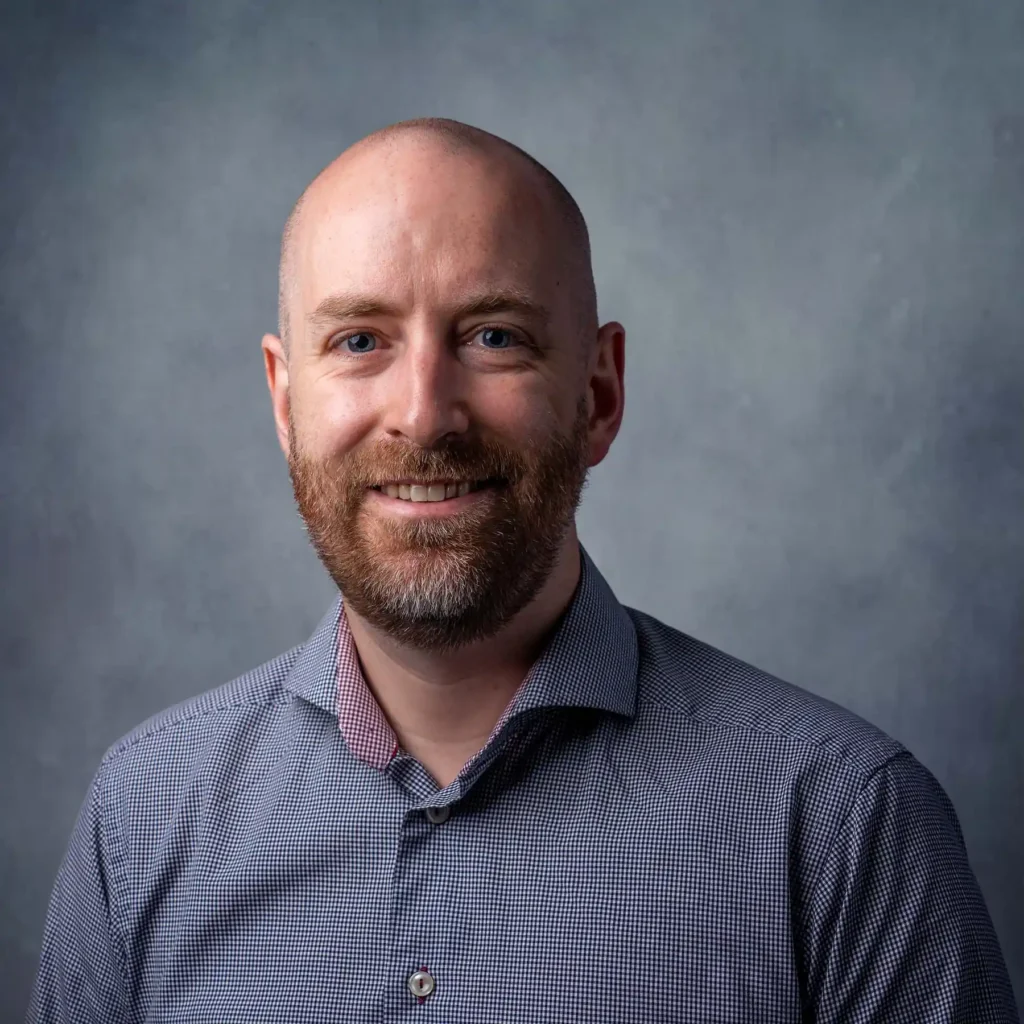 Professionellt personalporträtt av en leende man i rutig skjorta, fotograferad av företagsfotograf i Arvika.