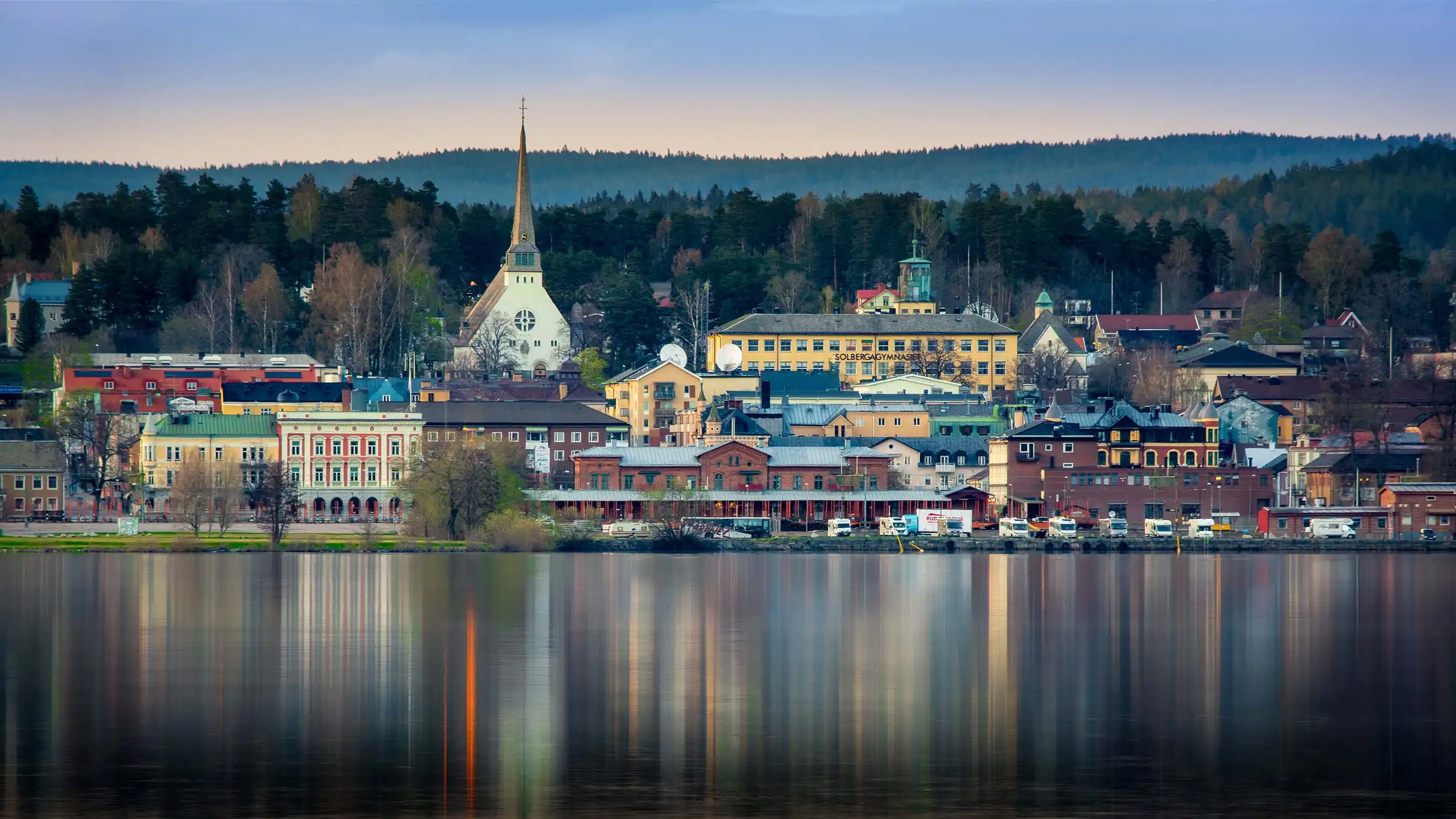 Stämningsfull vy över Arvika kyrka och hamn vid solnedgång, en professionell fotografs perspektiv från PixPep för priser och tjänster i Värmland.