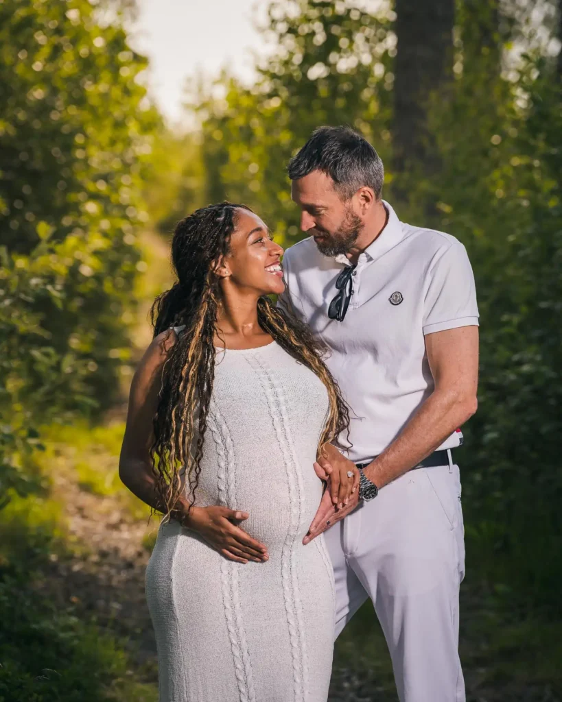 Gravidpar som ser lyckligt på varandra i en lummig grön miljö utanför Arvika, fångat av en professionell gravidfotograf från Arvika.