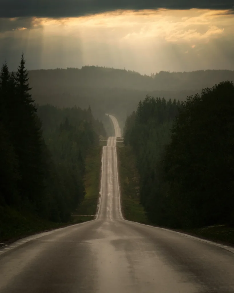 Dramatisk vy över en asfalterad väg som slingrar sig genom skogen mellan Torsby och Gräsmark. Naturfoto av PixPep, Arvika.